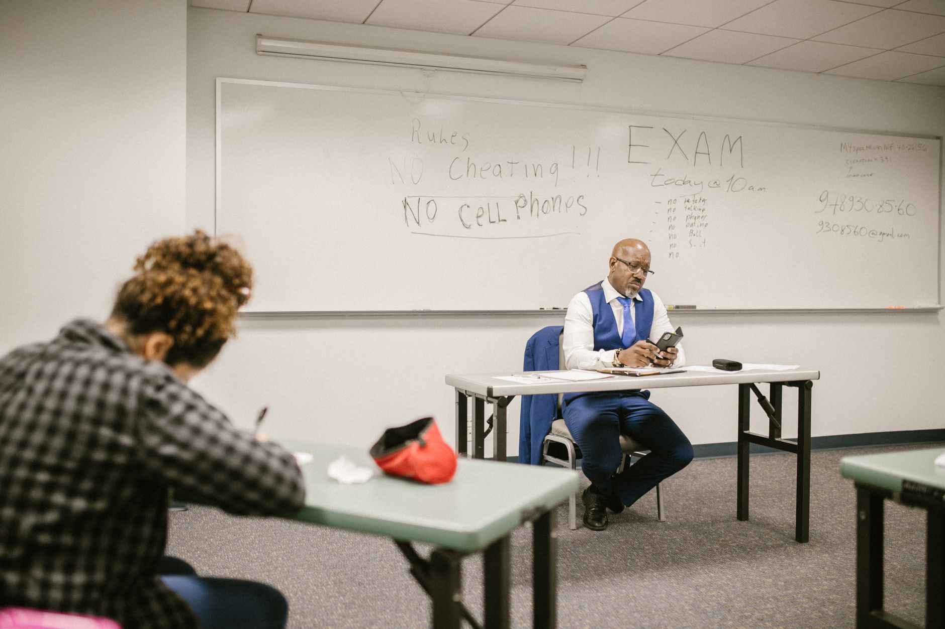 Proctor watching students take an exam in a classroom