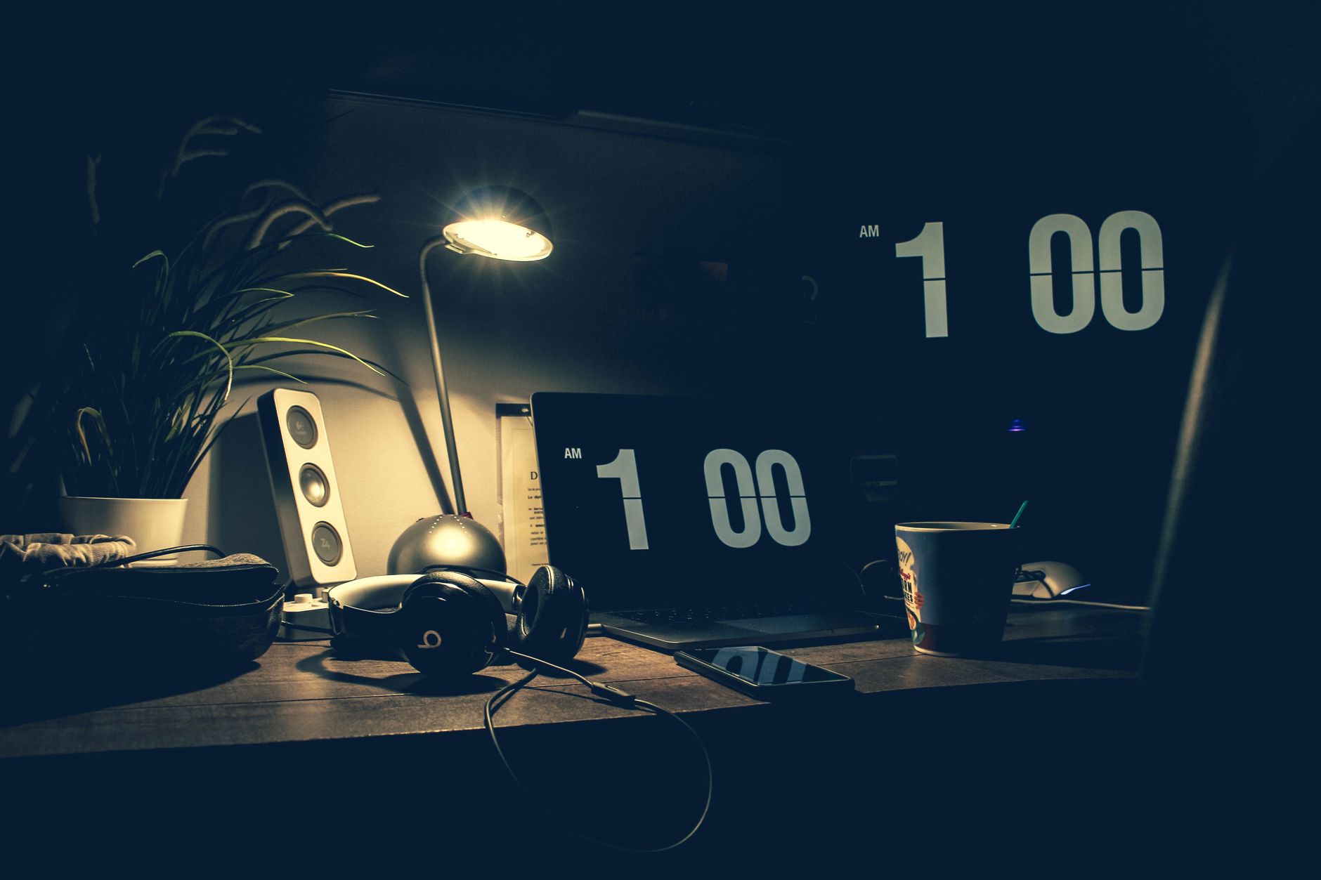 Dimly lit office desk with a laptop showing 1:00 AM